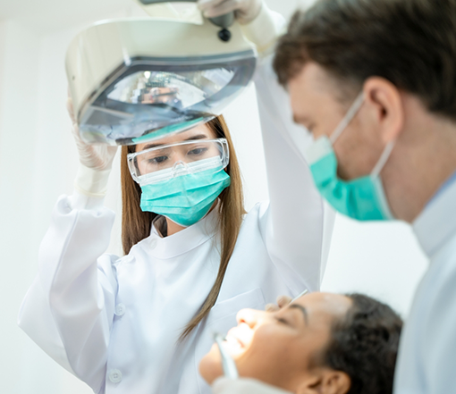 Dentist and assistant preparing to treat a patient